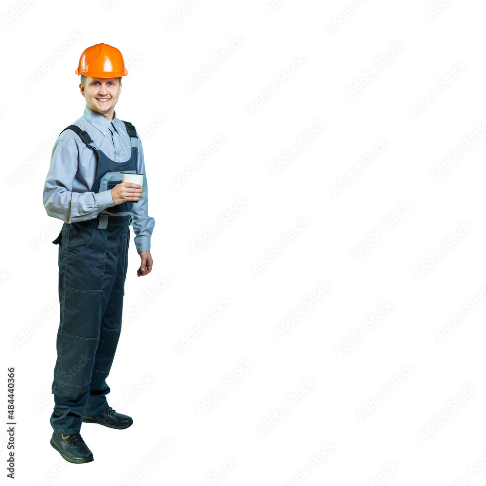 handsome young worker, engineer smiling at camera. the man decided to take a break and took a mug of hot tea and coffee. isolated. full height handsome young worker, engineer smiling at camera. the man decided to take a break and took a mug of hot tea and coffee. isolated. full height