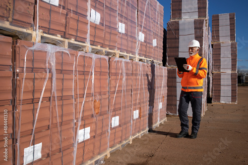 Construction worker supervisor doing inventory of construction materials at construction site.