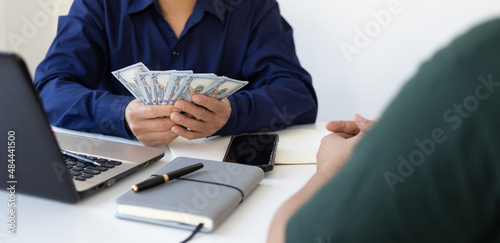 The young man waited to receive salary or wages from the boss. Businessman holding cash banknotes in the office.