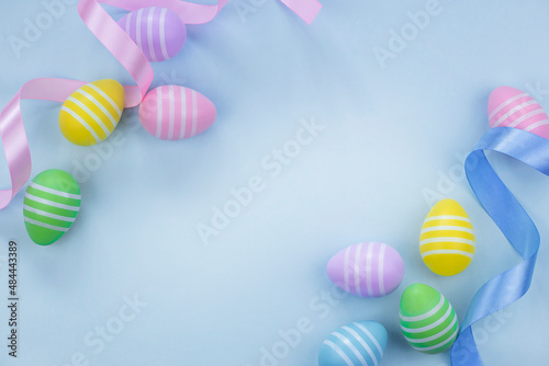 Top view of Easter eggs in pastel colors on light blue background with highlighted center. Flat lay image