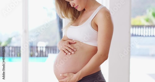 I love being big-bellied. Beautiful young pregnant woman rubbing her belly. Expecting mother standing alone and rubbing baby bump, touching pregnant tummy, enjoying pregnancy, love, care, anticipate photo