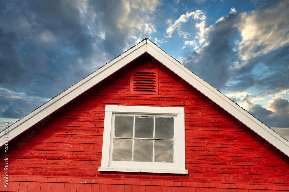 Peak of a rustic red building against a stormy sky.