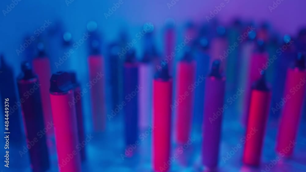 Lots of e-cigarettes and vapes in neon lighting. Concept of bad habits.