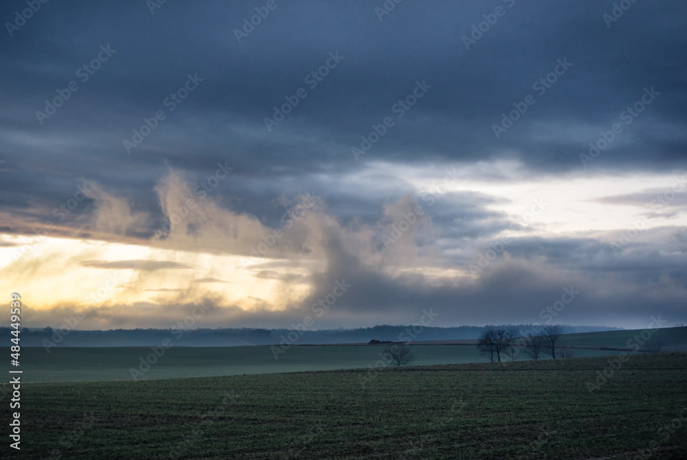  Evening landscape - sky with clouds over the meadows and forest.