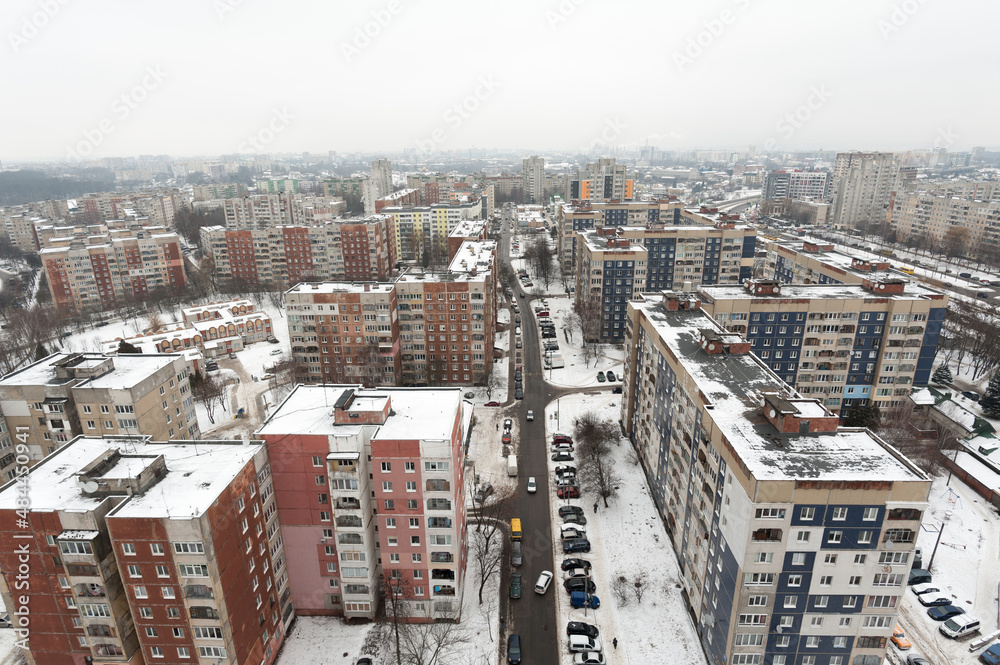 Fototapeta premium view from the window of a new building on the snow-covered roofs of houses in the old part of the foggy city