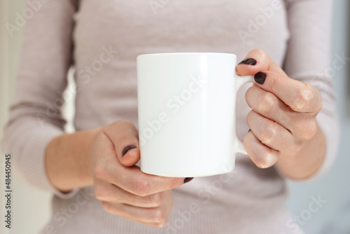 White coffee mug mockup for design demonstration. Stylish cup mock up in female hand.
