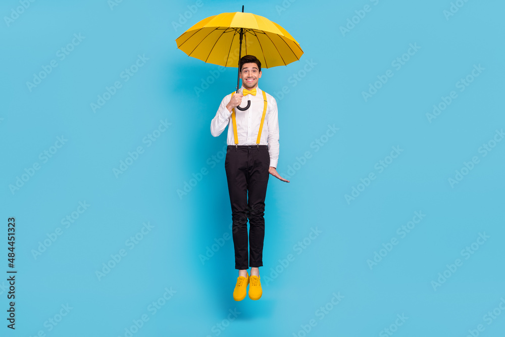 Full size portrait of crazy cheerful person hold umbrella rainy weather isolated on blue color background Full size portrait of crazy cheerful person hold umbrella rainy weather isolated on blue color background