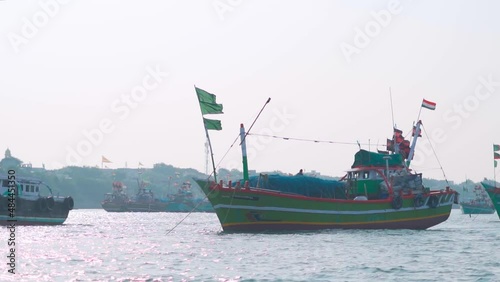 Boats in the Arabian sea at Okha Port in Gujarat, India. Fishing boats at the port with Indian flag on top of them. Small wooden fishing boats in the arabian sea.  photo