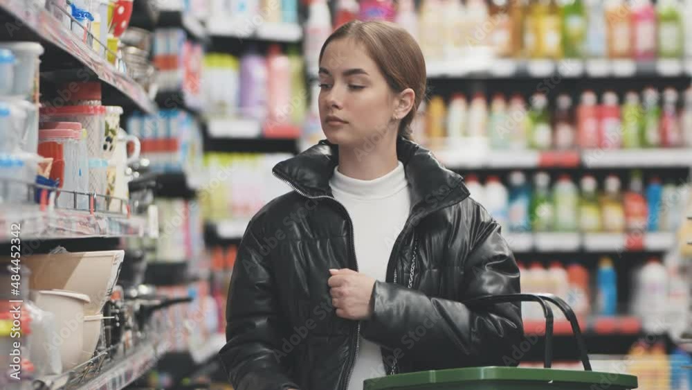 A young girl walks around the store with a basket. A young girl walks around the store with a basket.