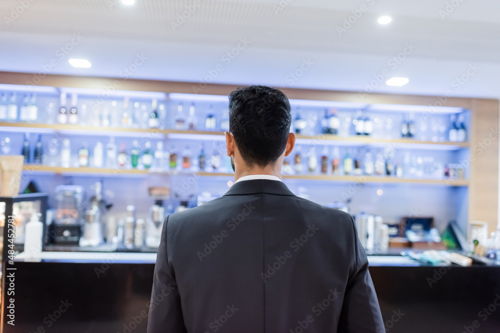 back view of young guard in blazer near blurred lobby bar in hotel. back view of young guard in blazer near blurred lobby bar in hotel.