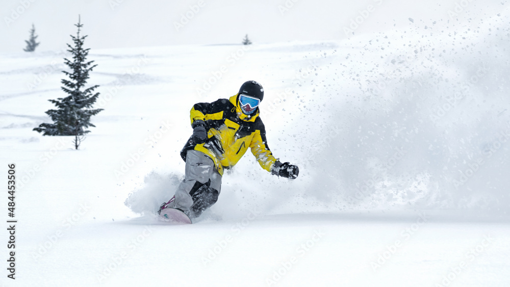Male freerider snowboarder going down the backcountry at high speed from a slope