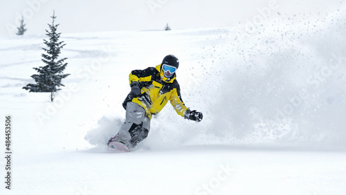 Male freerider snowboarder going down the backcountry at high speed from a slope