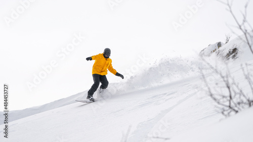 Freerider snowboarder rides down the picturesque alpine landscape. Fresh powder snow, blue sky on background.
