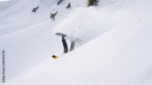Snowboarder falls on a snow-covered off-piste slope.