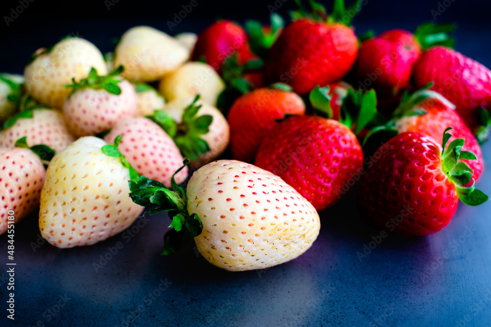 Close-up View of Whole Pineberries and Strawberries: Fresh red and white strawberries on a dark background Close-up View of Whole Pineberries and Strawberries: Fresh red and white strawberries on a dark background