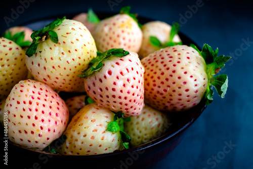 Freshly Washed Pineberries in a Wooden Bowl: Closeup view of wet white strawberries in a dark wood bowl photo