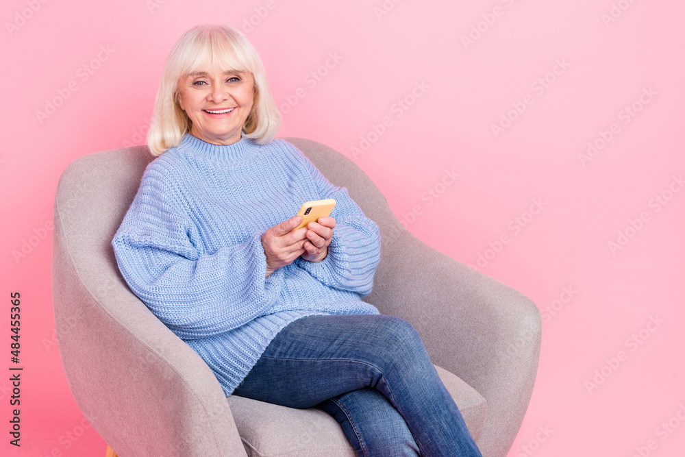 Fototapeta premium Portrait of attractive cheery grey-haired woman using gadget device blogging post app isolated over pink pastel color background
