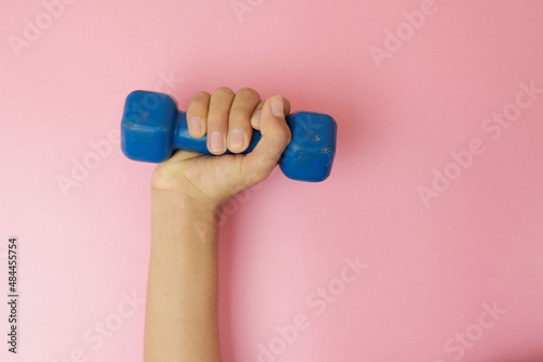 pesas para ejercitar los brazos. mancuernas de uso wn gimnasio. brazos cogiendo pesas con fondo claro photo