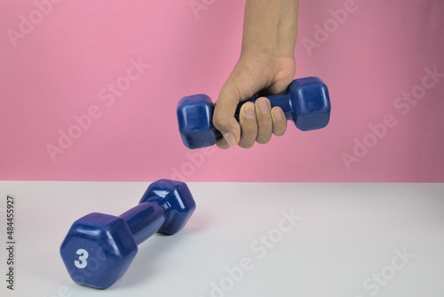pesas para ejercitar los brazos. mancuernas de uso wn gimnasio. brazos cogiendo pesas con fondo claro photo