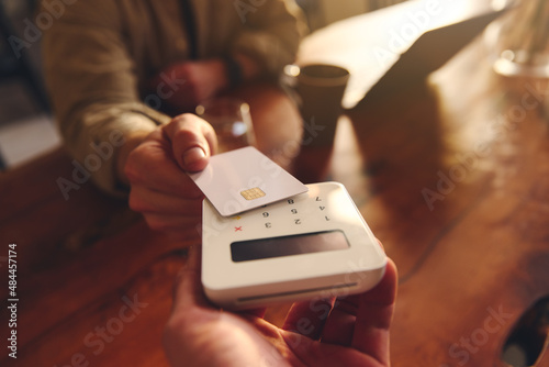 Canvas Print Hand tapping a credit card on a contactless card reader paying for coffee