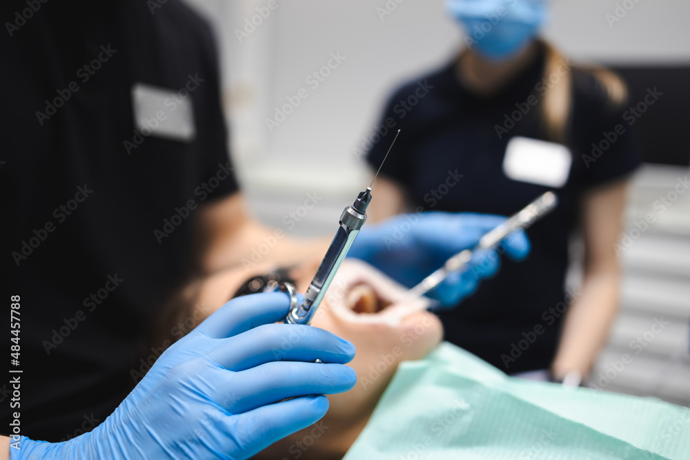 Dentist is going to inject anesthesia to the patient before starting dental treatment