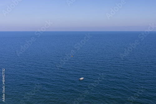 Panoramic view to Adriatic sea with small white motorboat and tiny yellow buoy on sunny day
