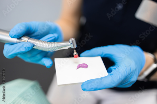 Close up view hand of a dentist doctor with a dental drill applies a cleaning paste on a brush. Concept of professional dental hygiene