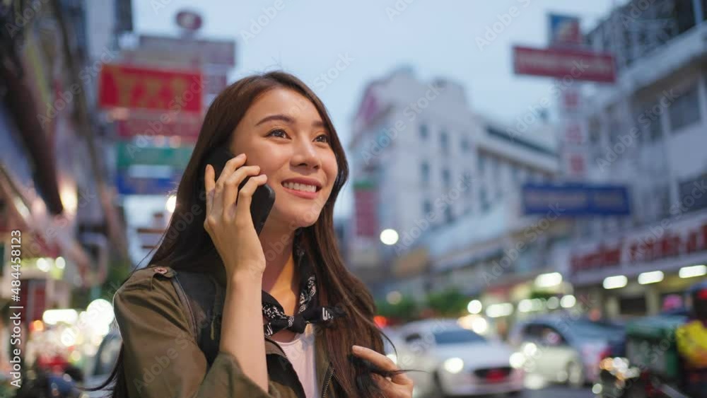 Asian attractive woman backpacker talking on phone while walk in city Asian attractive woman backpacker talking on phone while walk in city