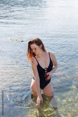 Fototapeta Naklejka Na Ścianę i Meble -  Girl in one-piece swimsuit comes out from sea