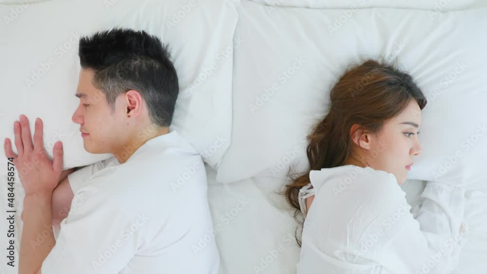 Asian young couple lying down on bed with painful after fight argument Asian young couple lying down on bed with painful after fight argument