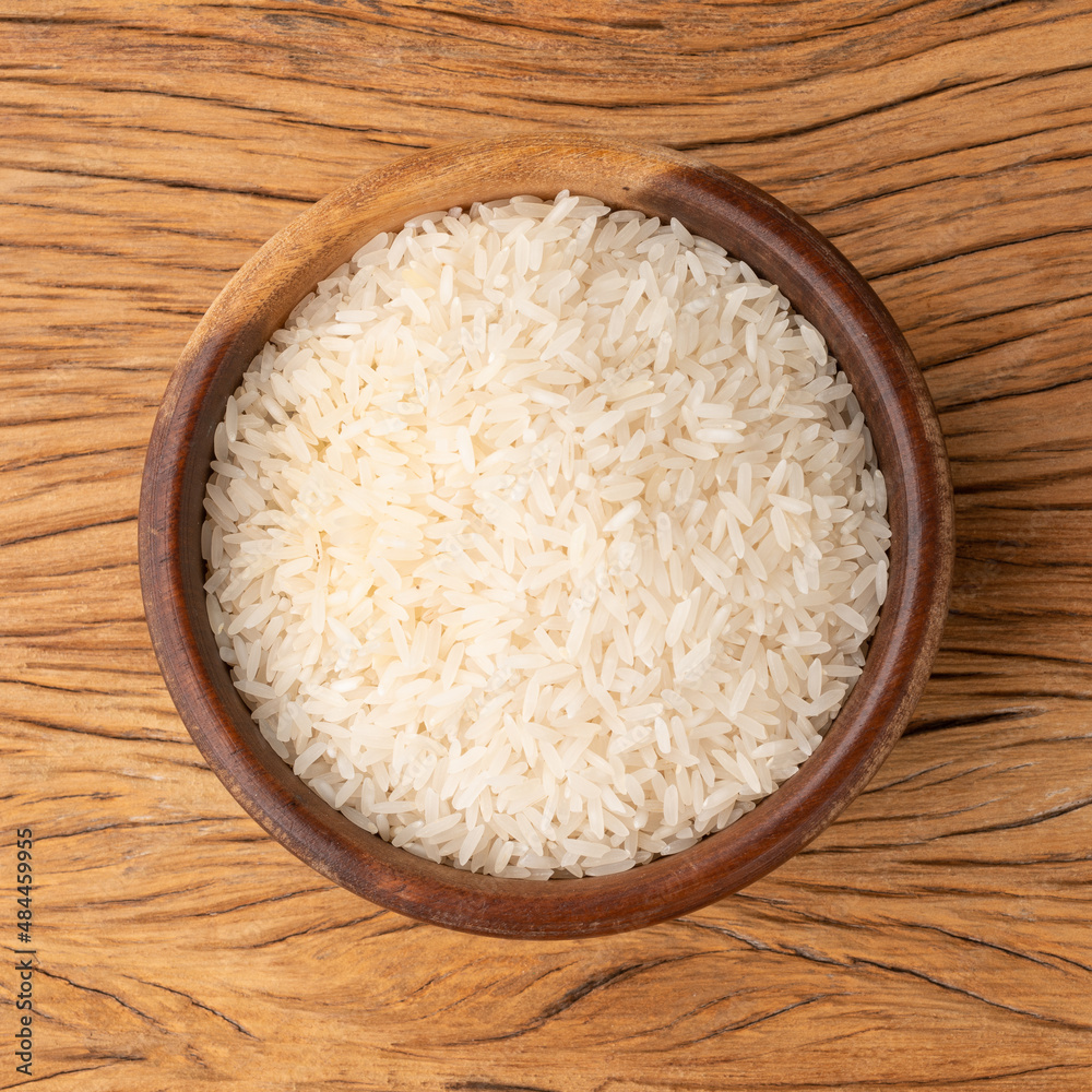 Raw white rice in a bowl over wooden table Raw white rice in a bowl over wooden table