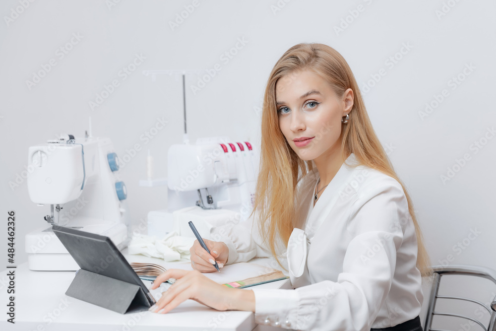 Female seamstress sitting working place with sewing tools and use tablet for online calls. Concept businesswoman tailor Female seamstress sitting working place with sewing tools and use tablet for online calls. Concept businesswoman tailor