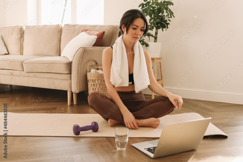 Athletic young millennial woman is engaged in sports training and exercise online in a room at home. A fitness blogger records videos during a workout using a smartphone and laptop. Selective focus Athletic young millennial woman is engaged in sports training and exercise online in a room at home. A fitness blogger records videos during a workout using a smartphone and laptop. Selective focus