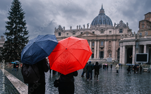 Young couple under umbrellas standing near St Peter s basilica at Vatican. Holidays for couple in Italy