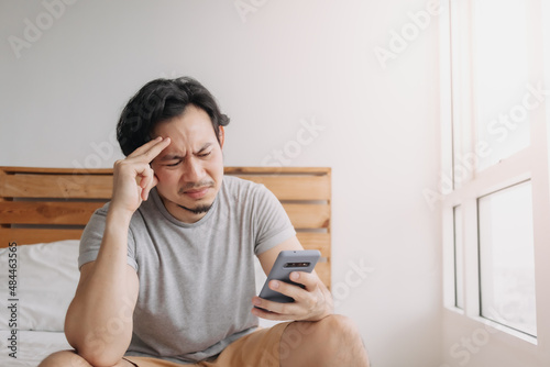 Sad Asian man has bad online chat news and feels disappointed on the smartphone.