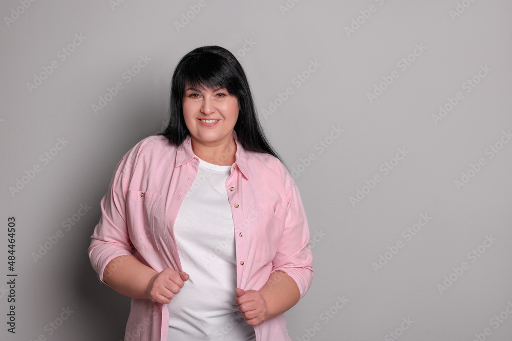 Beautiful overweight mature woman with charming smile on light grey background. Space for text Beautiful overweight mature woman with charming smile on light grey background. Space for text