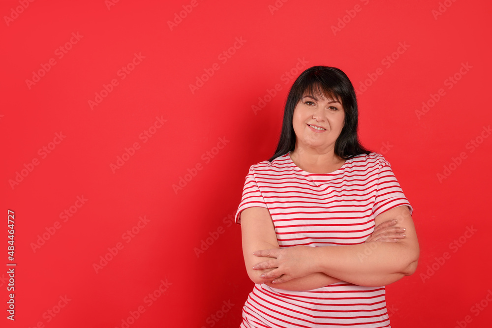 Beautiful overweight mature woman with charming smile on red background. Space for text Beautiful overweight mature woman with charming smile on red background. Space for text