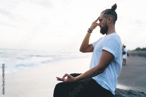 Caucaisan male yogi thinking about zen mindfulness doing pranayama asana at nature,man relaxing during morning workout for searching harmony during meditation practice and holistic healing for retreat