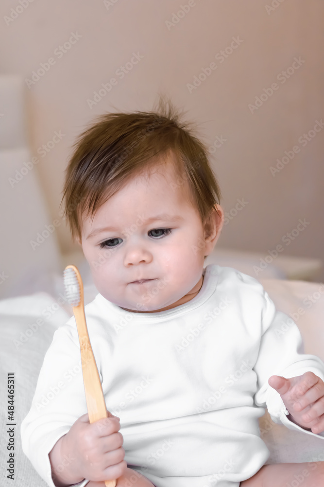 Cute baby saw the toothbrush for the first time, looks at it with interest. The first teeth cleaning for a small child Cute baby saw the toothbrush for the first time, looks at it with interest. The first teeth cleaning for a small child