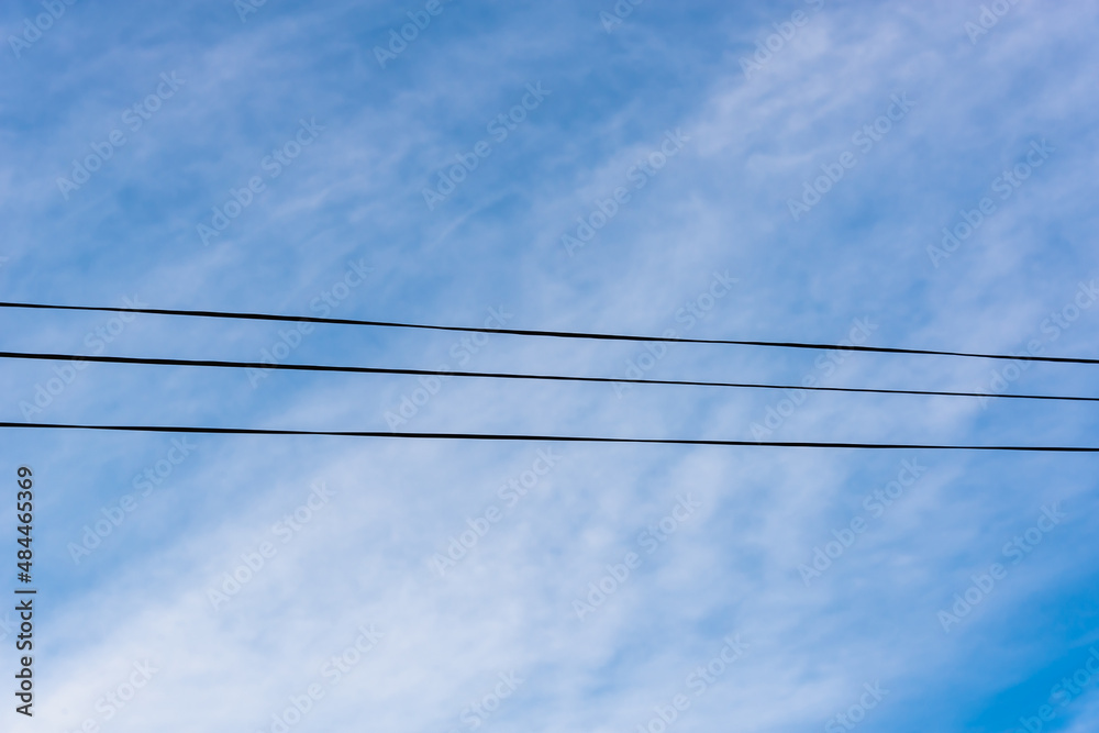 Wires against the blue sky with clouds. Three wires.