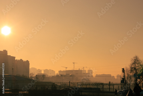 Dawn over the foggy city. Rising sun over a large construction site on the horizon
