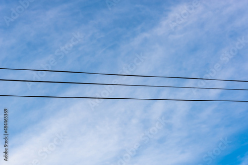 Wires against the blue sky with clouds. Three wires.