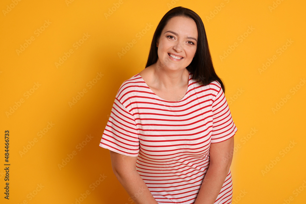 Obraz premium Beautiful overweight woman with charming smile on yellow background. Space for text