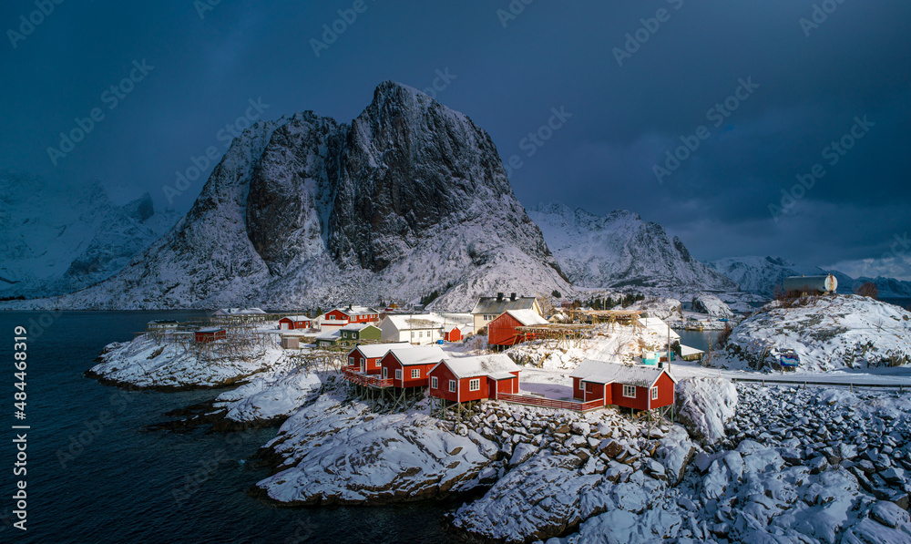 Norwegian village in cloudy weather against the backdrop of a large rock