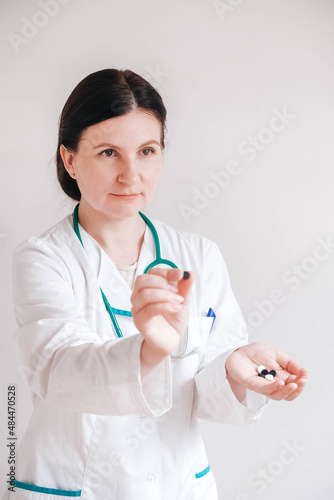 Woman doctor with pills in her hands on a white background. Taking vitamins or medications. Copy  empty space for text