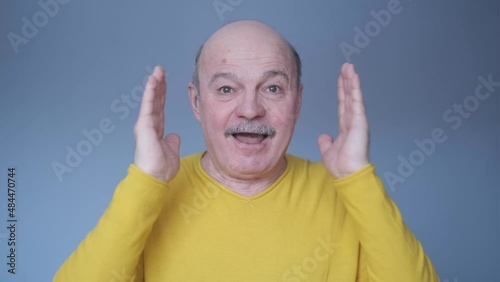Bald senior man being shocked with surprise expression and excited face.