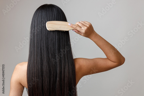 Fotografie Brunette young woman brushing hair in studio
