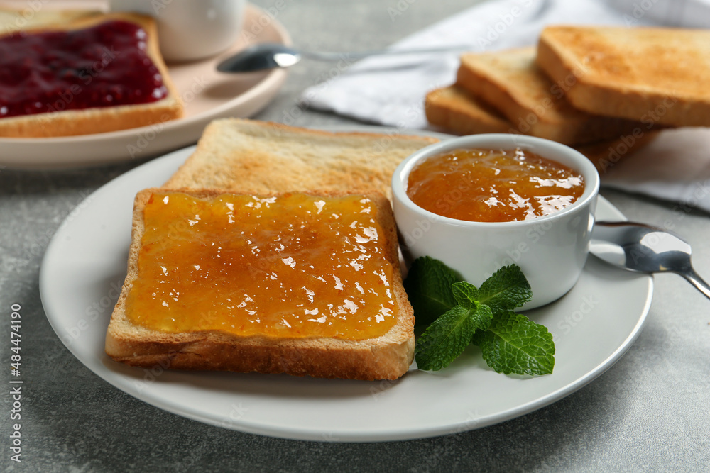 Delicious toasts served with jam and mint on light grey table, closeup Delicious toasts served with jam and mint on light grey table, closeup