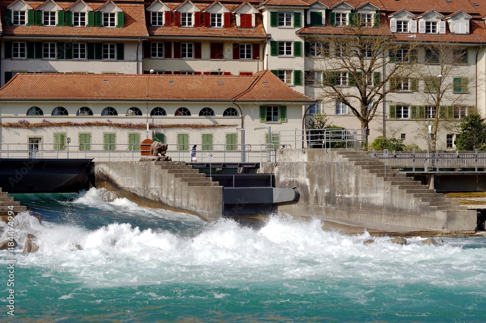 Floodgates or flood locks on the river Aare in Bern, Switzerland. They regulate the water flow. There are historic residential houses built along the riverbank.
