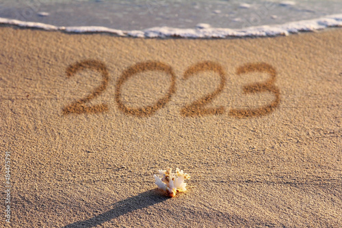 Ein Sandstrand mit Meer und Muschel mit der Jahreszahl 2023 photo